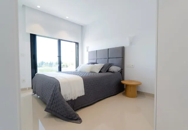 Dormitorio con paredes blancas mate y gran ventanal