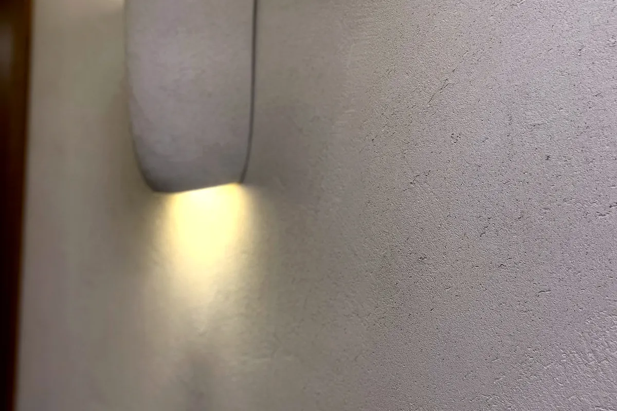 Luz de aplique sobre pared de cal junto al marco de una puerta