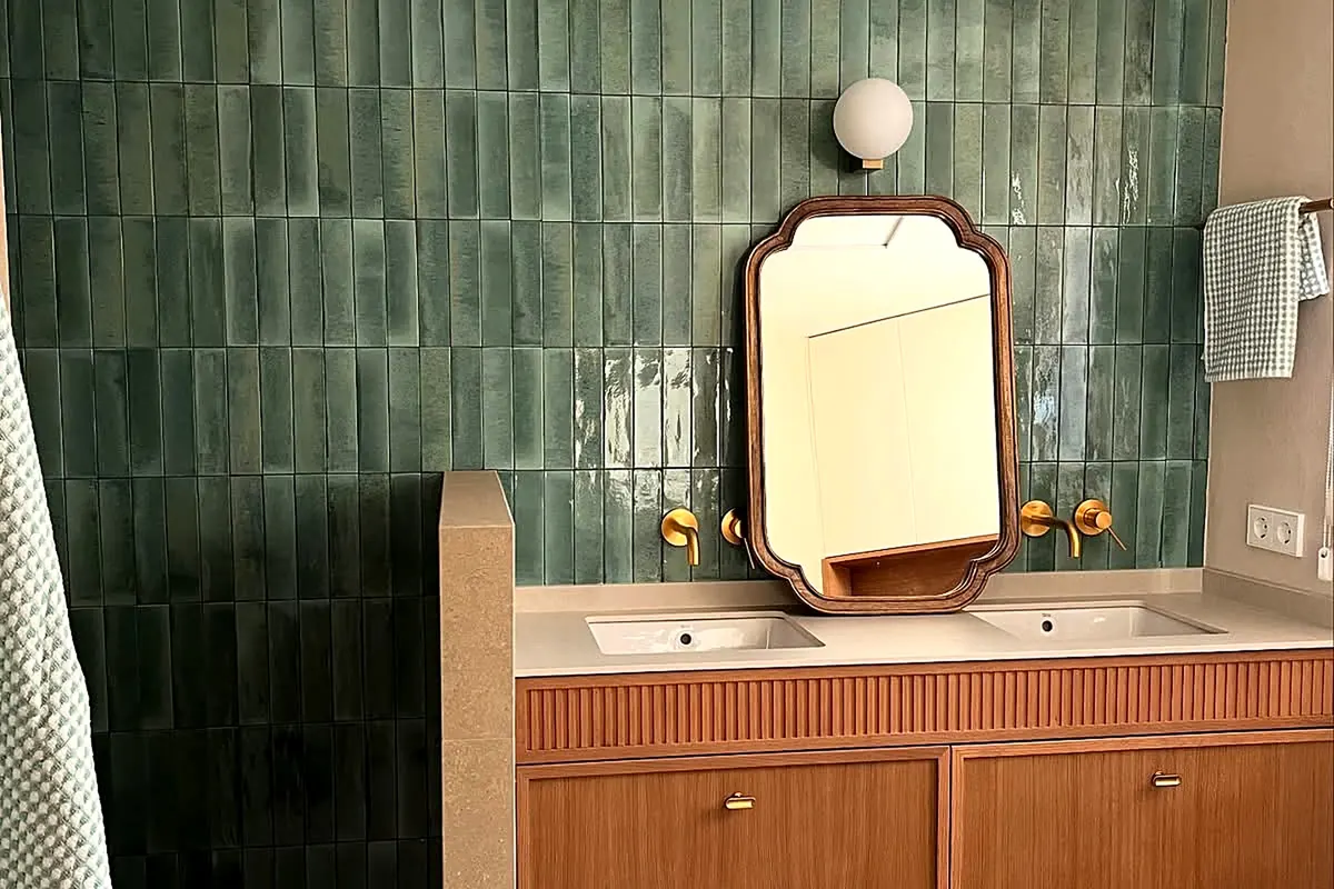Baño con paredes de cal, azulejo verde y mueble de lavabo de madera
