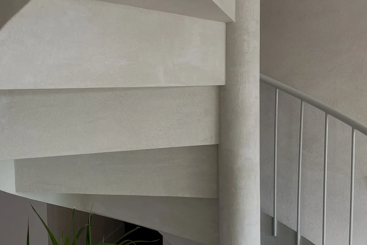 Detalle del giro de la escalera de microcemento y la pared de cal
